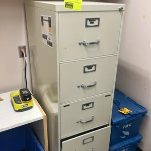 Metal 5-drawer vertical filing cabinet. Features a beige finish, classic metal pull handles, and integrated label holders. Contents and surrounding it