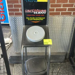 CartWipes metal cart wipe dispenser stand. Features an integrated top sign holder with Homeland CartWipes graphics, a plastic center wipe dispenser li