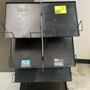 Metal multi-tier newspaper merchandiser rack. Features six angled display shelves with wire book and paper retainers and a flat bottom base shelf. Gra