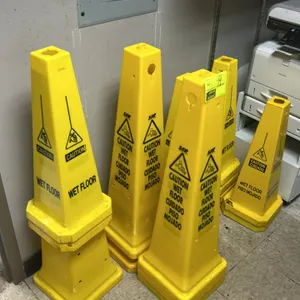 Poly wet floor cone. Features yellow plastic construction with a four-sided design. Printed with bilingual 'Caution Wet Floor / Cuidado Piso Mojado' w