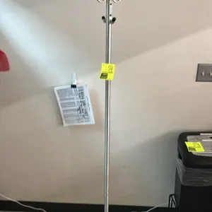 Metal coat hanging rack. Features a brushed metal upright post with multiple coat and hat hooks, finished with protective caps. Supported by a weighte