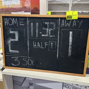 Wooden framed chalkboard. Features a black writing surface with a light-colored wood frame. 3'L x 2'H. Currently written on in chalk.