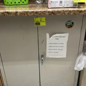 Metal 2-door storage cabinet. Features a tan finish, two interior shelves, and a latching handle. Includes various interior contents as shown, includi