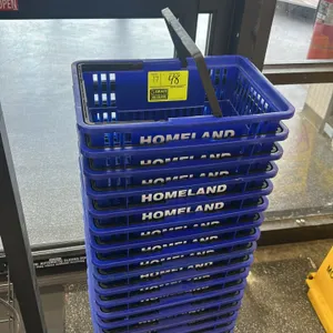Stack of poly grocery baskets. Features blue plastic construction with 'HOMELAND' branding and dual folding carry handles. Includes wire metal nesting