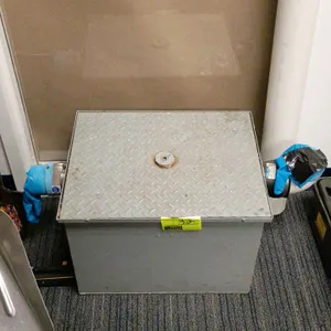 Commercial grease trap interceptor. Features a durable gray-coated steel body with a slip-resistant diamond-plate lid and center securing bolt. Equipp