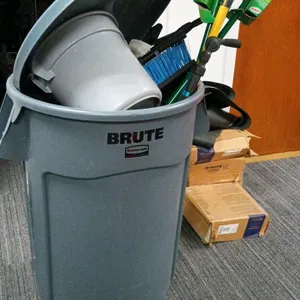 Janitorial supply lot. Includes a Rubbermaid Brute rolling trash can with lid, a Quickie floor squeegee with yellow fiberglass handle, Libman scrub br