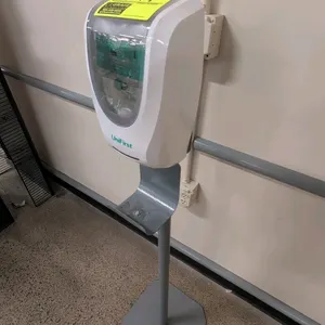 UniFirst automatic hand sanitizer dispenser. Features white plastic housing with a clear product viewing window. Mounted on a grey metal pedestal stan