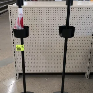 Metal poly bag stand. Features a black finished metal construction, weighted round base, central upright pole, mid-level dispenser basket, and top rol