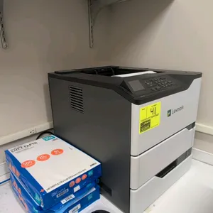 Lexmark MS725 laser printer. Features built-in control panel with LCD display and keypad. Includes three 500-sheet packs of 8.5" x 14" copy paper and 