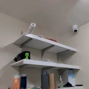 Laminate 3-tier wall-mounted shelving unit. Features three white laminate shelves with metal wall standards and support brackets. Includes various con