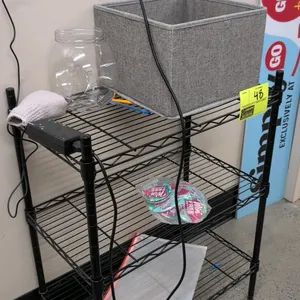 Metal 3-tier wire shelving unit in a black finish. Includes pictured contents: fabric storage bin, plastic jar, mesh zipper pouch, and miscellaneous i