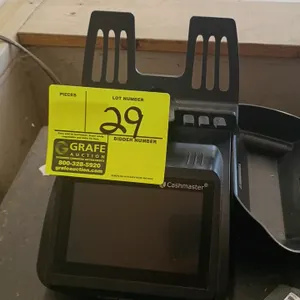 Cashmaster electronic money counter. Features a digital display screen, top-mounted weighing platform, and includes one black plastic till scoop. Powe