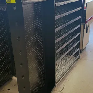Double-sided check lane display unit. Features black metal construction with pegboard backing, wire shelving, and hanging product hooks. Mounted on ca