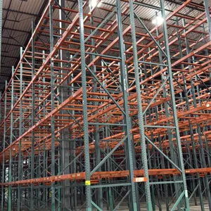 Interack pallet racking. Features green upright frames and orange 3.5" cross bars, with approximately 4-decks per section. Dimensions per bay: 8' x 3'