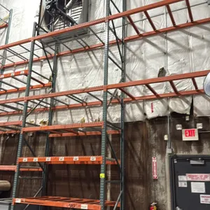 Interack pallet racking system. Features green teardrop-style uprights, orange 3.5" cross bars, and wire mesh decking. Configured with approximately 4