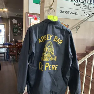 A Vintage Abbey Bar Button-Up Coach Jacket. (Abbey Bar, circa 1980s-1990s) A black nylon windbreaker jacket featuring yellow screen-printed graphics o