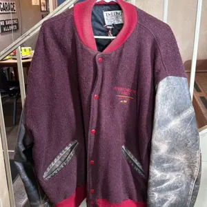 A Westchester Abbey Golf Team Letterman's Jacket. (DeLONG, 1990) A vintage varsity jacket with a maroon wool body and leather sleeves. Features "WESTC