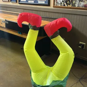 Inflatable elf legs holiday decoration. Features an upside-down elf legs design with yellow legs, red curled boots, and a green collar base. Equipped 