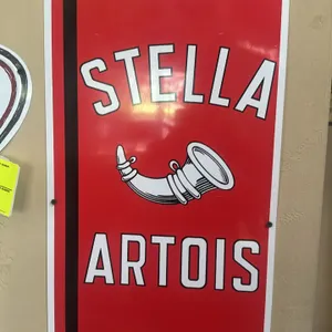 A Stella Artois Metal Advertising Sign. (Stella Artois, 2010s) A metal advertising sign featuring the brand's classic red, black, and white color sche