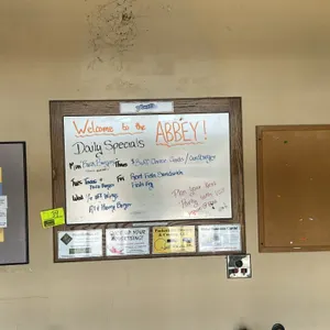 Assorted wall-mounted boards. Includes (1) whiteboard with a wood frame and advertising card slots, (1) cork board with a light wood frame, and (1) gr