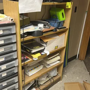 Laminate multi-tier bookshelf with assorted office supplies and electronics. Features wood-look laminate construction. 3'x1'. Includes remaining conte