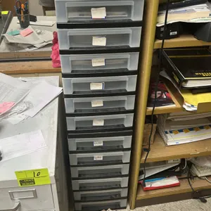 Poly multi-tier drawer organizer. Features a black plastic frame with translucent pull-out drawers. Modular, stackable design. Contents not included.