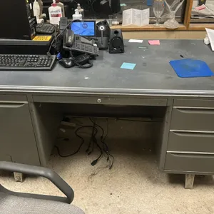 Metal double-pedestal desk with rollable office chair. Desk features a gray metal frame, laminate top, single left cabinet, three right drawers, and a