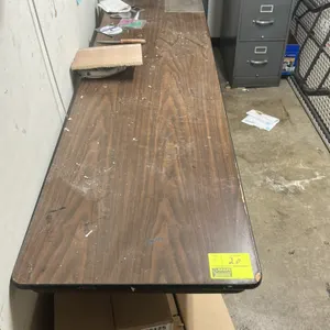 Foldable table lot. Includes one laminate folding table and one poly folding table. The laminate table features a wood-grain style top and measures 8'