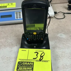 Motorola handheld mobile computer barcode scanner. Features an integrated barcode scanner, alphanumeric keypad, tethered stylus, and rear hand strap. 
