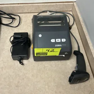 Zebra ZD420 desktop thermal label printer. Includes a wired handheld barcode scanner and power supply adapter. Canon calculator in background is not i