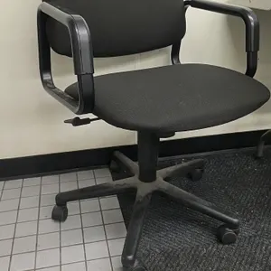 Portable task office chair. Features black fabric upholstered seat and backrest, integrated plastic armrests, and pneumatic height adjustment. Mounted