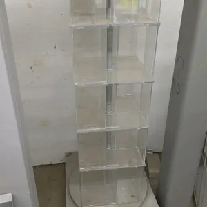 Revolving merchandiser display. Features a multi-tier clear acrylic rotating compartment assembly mounted on a central metal support post. Designed fo