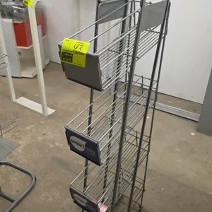 Metal merchandiser display rack. Features four angled wire basket shelves with Smartwater branded graphics. Designed with a slim profile and mounted o