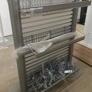 Double-sided metal merchandiser display rack. Features slatwall style panels, adjustable wire display baskets, and assorted metal peg hooks. Mounted o