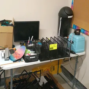 Office supply and table package lot. Includes a 4' white poly folding table, a Dell LCD monitor, a black metal mesh desk organizer, a blue hand-pump s