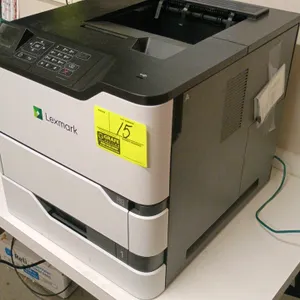 Lexmark MS725 monochrome laser printer. Features a built-in control panel with a small display screen, physical numeric keypad, and a front-loading pa
