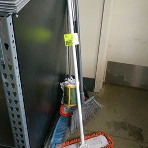 Assorted cleaning tools and brooms. Includes an upright angle broom, an orange microfiber dust mop, a wet string mop, and a blue hand brush. Shelving 