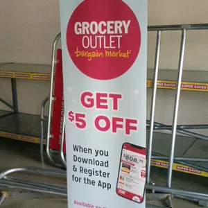 Retractable roll-up marketing banner featuring Grocery Outlet Bargain Market branding. Graphics promote mobile app registration with 'GET $5 OFF' text