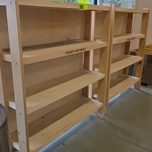 Valued Naturals wooden shelving merchandiser. Features a light-colored wood construction with four shelves. Front edge of the second shelf is branded 