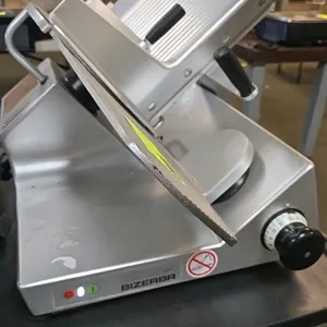 Bizerba GSP manual gravity feed deli slicer. Features a 13" blade, adjustable slice thickness, and anodized aluminum construction. Mounted on rubber f