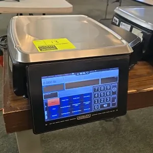 Hobart HTi digital pricing scale. Features a touchscreen user interface, rear customer display screen, integrated label printer, and stainless steel w