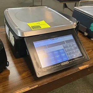 Hobart HTi digital pricing scale. Features a touchscreen user interface, integrated label printer, rear customer display screen, and stainless steel w