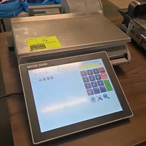 Mettler Toledo UCCW digital pricing scale. Features a touchscreen operator interface, rear-facing customer display screen, integrated label printer, a