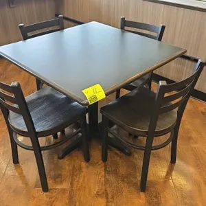 Table and chair set. Includes one 36" x 30" table featuring a dark laminate top and a black metal pedestal X-base. Accompanied by four matching black 