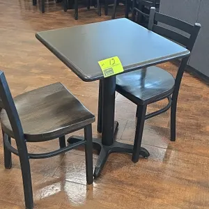 Table and chair set. Includes one 24" x 30" table with a black laminate top and black metal pedestal base, and two matching ladder-back chairs featuri