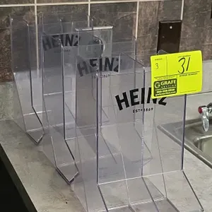 Heinz 2-section condiment merchandiser. Features clear plastic construction with two vertical compartments and printed Heinz logo on the front.