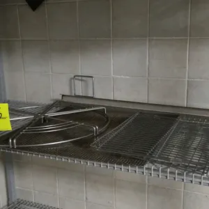 Assorted stainless steel and wire rack contents. Includes one circular wire carousel rack, two rectangular wire grates, a perforated stainless steel s