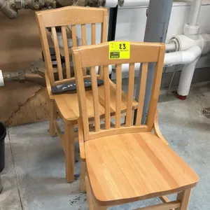 Wooden dining chair. Features a solid wood construction with a light natural finish, vertical slat back design, and a contoured seat. Supported by a s