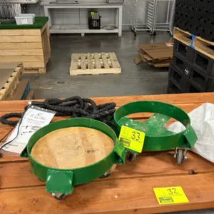 Uline metal 5-gallon bucket dolly. Features green painted steel construction with a cross-brace frame and four swivel casters. Designed to easily mobi