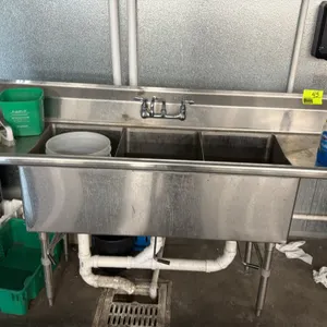 Advance Tabco stainless steel 3-compartment sink. Features left and right drainboards, splash-mount faucet, and integrated backsplash. Includes wall-m